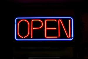 Neon 'Open' sign glowing brightly, commonly seen in storefronts